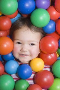 a child's face sorrounded by colorful plastice balls
