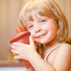 a smiling kid holding a spill proof bottle