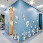 Corner view of hallway with light blue walls covered in white 3D sea creature cutouts, wooden doors, and large windows letting in natural light.